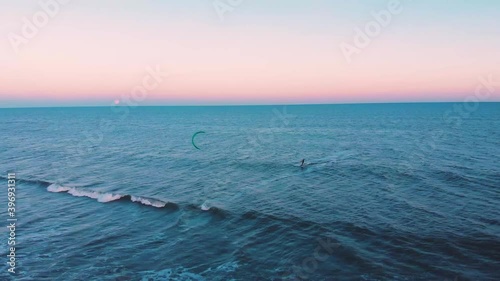Kitesurfing alone in blue wide ocean during colorful peaceful sunset