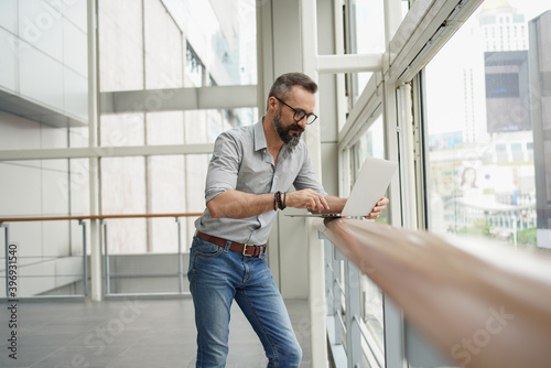 Lifestyle of man hipster freelancer standing and holding laptop at office terminal corporate, professional freelance man concept Free Download Lifestyle of man hipster freelancer standing and holding laptop at office terminal corporate, professional freelance man concept - GFXLoad