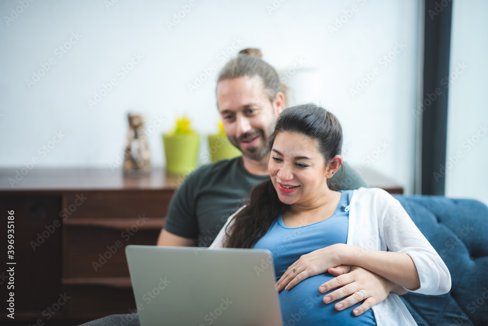 Lovely pregnant couple using laptop while resting