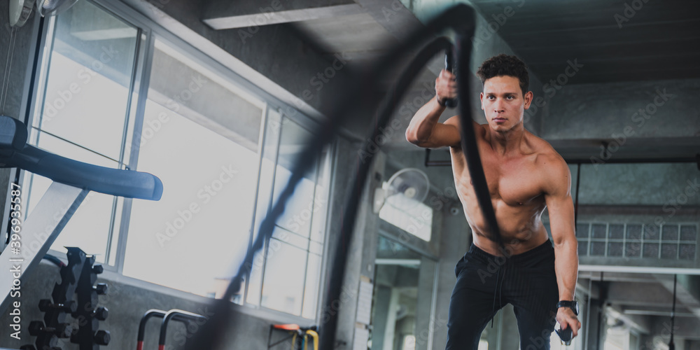 handsome and strong young man working out, Doing intense exercise in the sport gym, Attractive tall muscular bodybuilder doing heavy in modern fitness center. handsome and strong young man working out, Doing intense exercise in the sport gym, Attractive tall muscular bodybuilder doing heavy in modern fitness center.