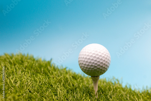 Golf ball is on green grass with blue sky background