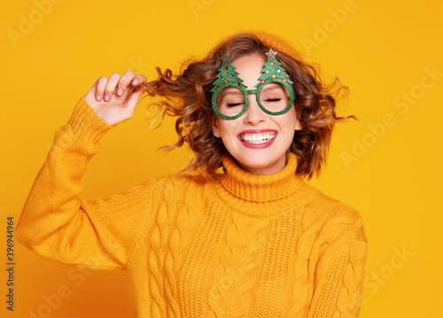 Delighted woman in Christmas glasses touching hair.