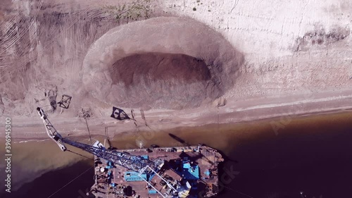 A dredger unloads sand onto the shore from a dump scow