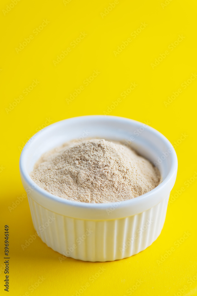 Lecithin powder in a bowl on a yellow background. Lecithin powder in a bowl on a yellow background.