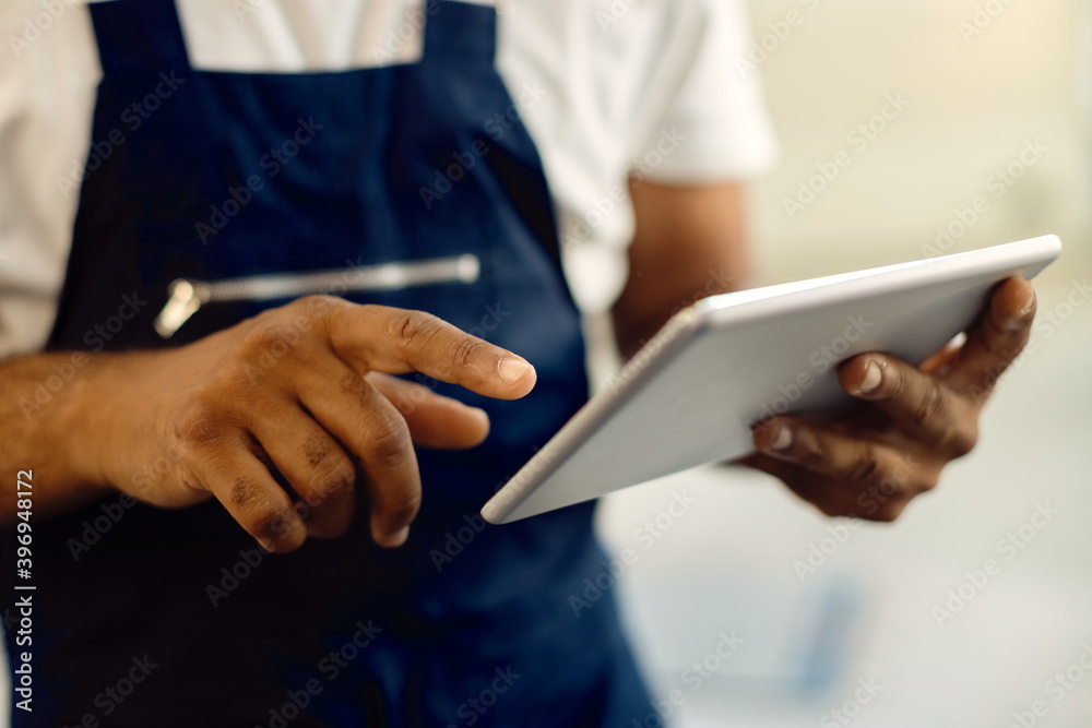 Close-up of mechanic working on digital tablet in auto repair shop. Close-up of mechanic working on digital tablet in auto repair shop.