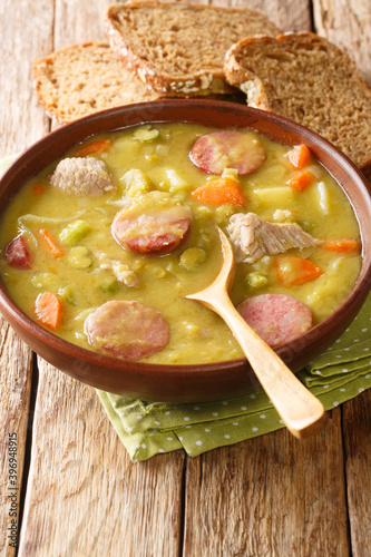 Snert Split Pea Soup with vegetables,  smoked sausages and pork closeup in the plate on the table. vertical photo