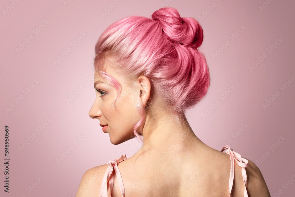 Beautiful young woman with unusual hair on pink background
