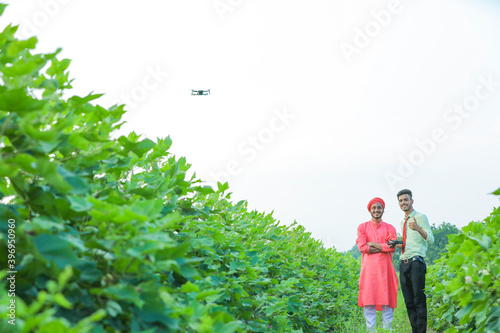 young indian agronomist and farmer using drone for checking at agriculture field