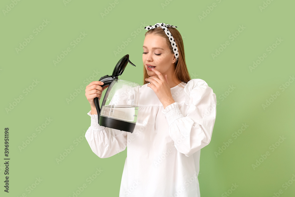 Young woman holding electric kettle on color background Young woman holding electric kettle on color background