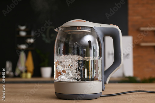Valokuva Electric kettle with boiling water on kitchen table