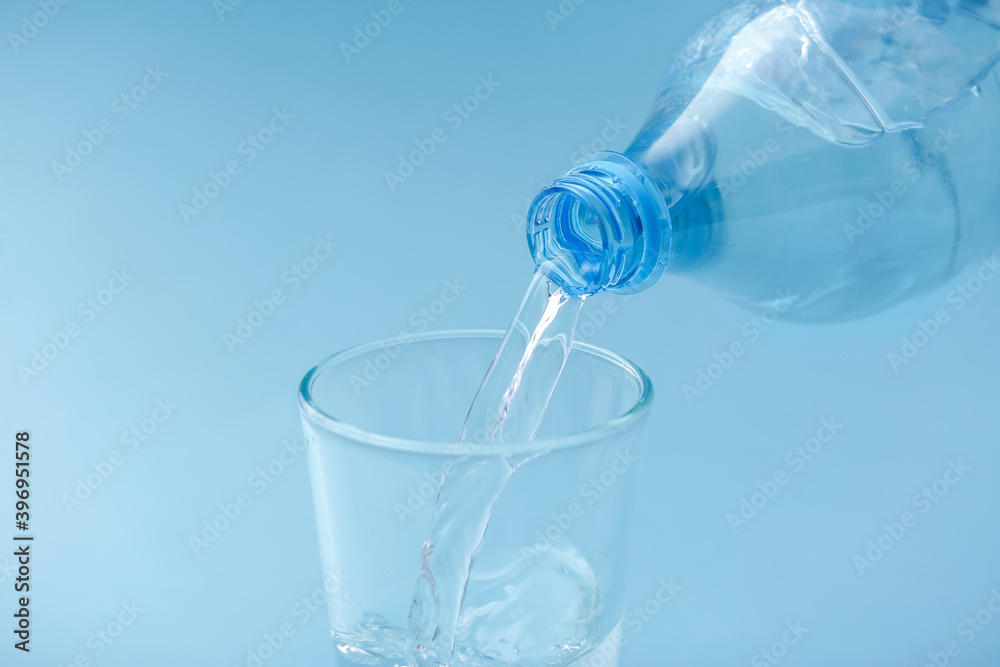 Pouring of water into glass on color background Pouring of water into glass on color background