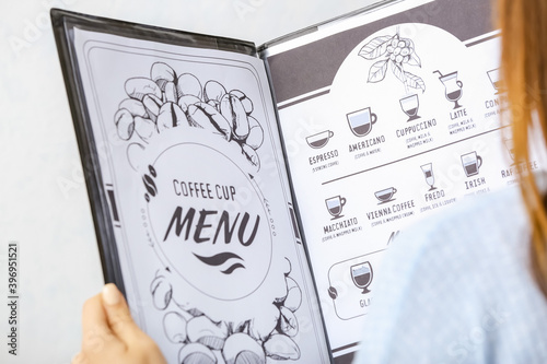 Woman reading menu in cafe,...