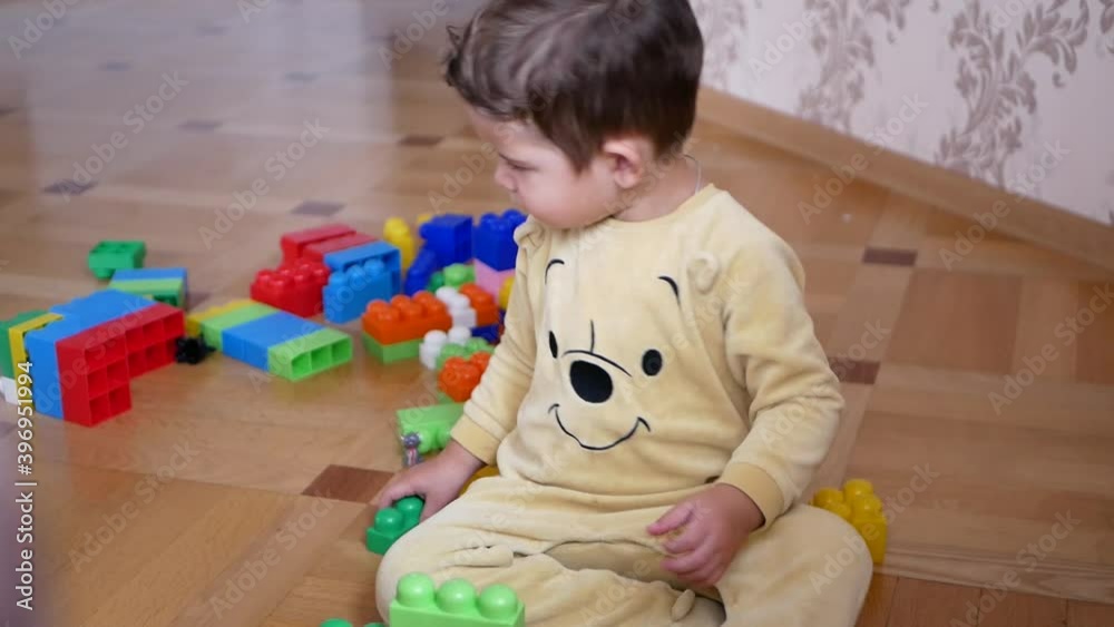Little boy in cute pajamas playing with colorful blocks on the floor. Home schooling and educational games concept Little boy in cute pajamas playing with colorful blocks on the floor. Home schooling and educational games concept