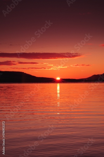 太陽の光に紅く染まる湖の風景。陽光の下のカルデラ湖の明媚な瞬間。