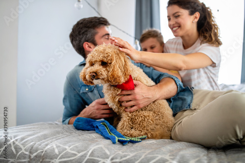 Happy young friendly family spending fun times together and cuddling with their pet at home