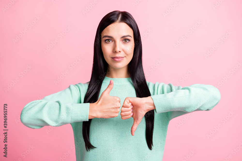 Photo portrait of woman showing thumb up down sign isolated on pastel pink colored background Photo portrait of woman showing thumb up down sign isolated on pastel pink colored background