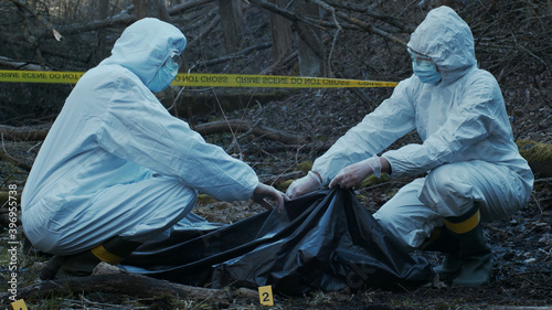 Detectives are collecting evidence in a crime scene. Forensic specialists are making expertise. Police investigation in a forest.