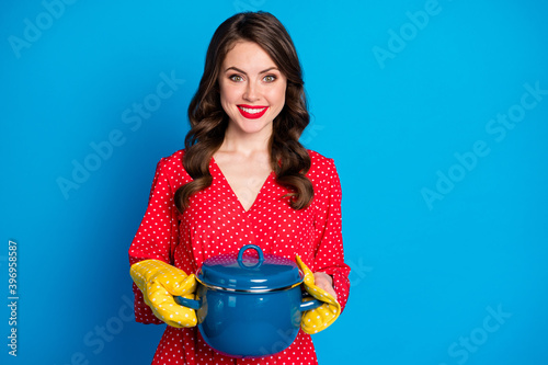 Photo of young happy smiling cheerful good mood positive girl housewife hold pot in gloves isolated on blue color background