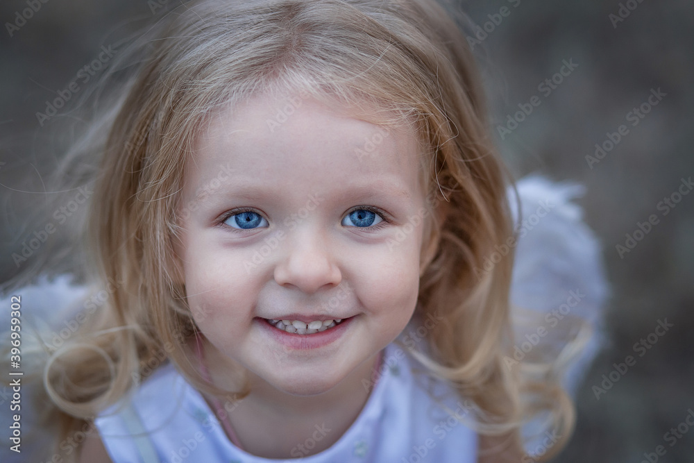 Portrait of a beautiful smiling angel girl. Cute curly blonde with blue eyes. Portrait of a beautiful smiling angel girl. Cute curly blonde with blue eyes.