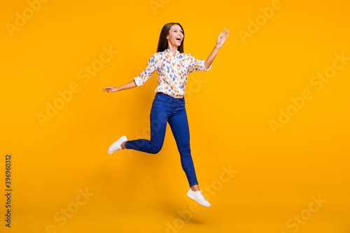 Full length photo portrait of graceful woman walking looking in distance jumping up isolated on bright yellow colored background
