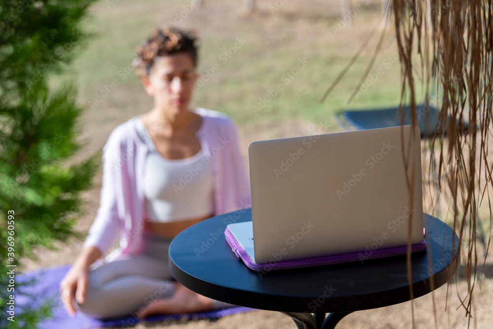 Yoga trainer holding online class during pandemic Coronavirus. Fitness coach teaching yoga online to group of people near the sea side in hotel garden. working outside, untethered employers, gig econo