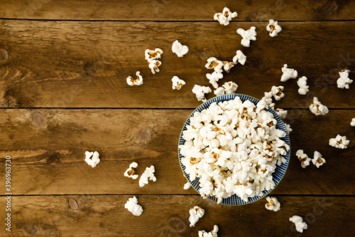 A bowl of salty popcorn on wooden background