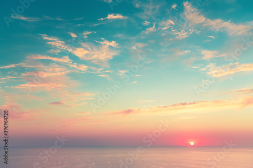 Sea view at sunset. Summer travel background. Vintage filter. Beautiful blue sky with clouds and sun on the horizon of the sea.