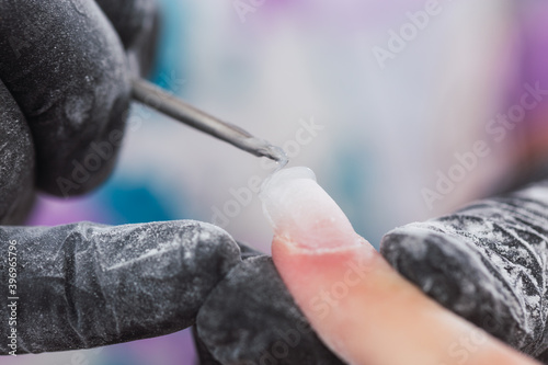 Professional manicure working with nail extension gel - Close-up of a manicurist working on nails. photo