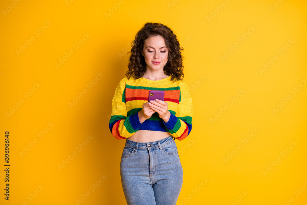 Photo of nice optimistic curly hairstyle young woman read message wear top jeans isolated on bright yellow background Photo of nice optimistic curly hairstyle young woman read message wear top jeans isolated on bright yellow background