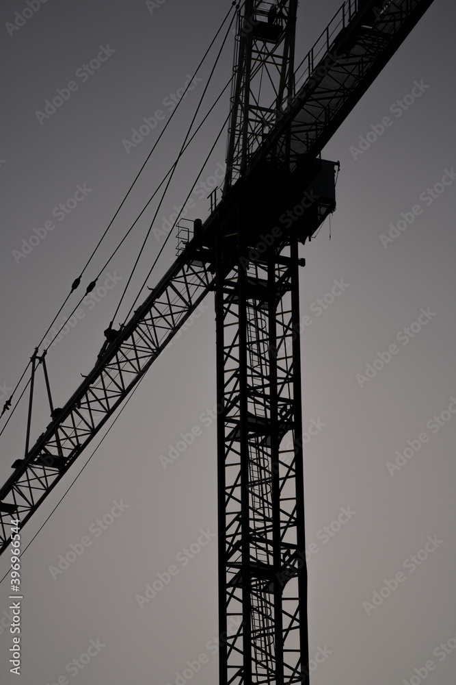 Silhouette of a construction crane on gray sky background