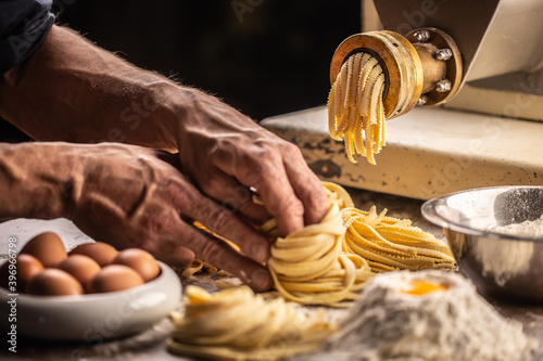 Pasta making machine and fresh spaghetti or fettuccine pasta shaped into nests