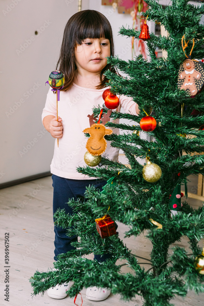 Little brunette girl decorating the christmas tree at home