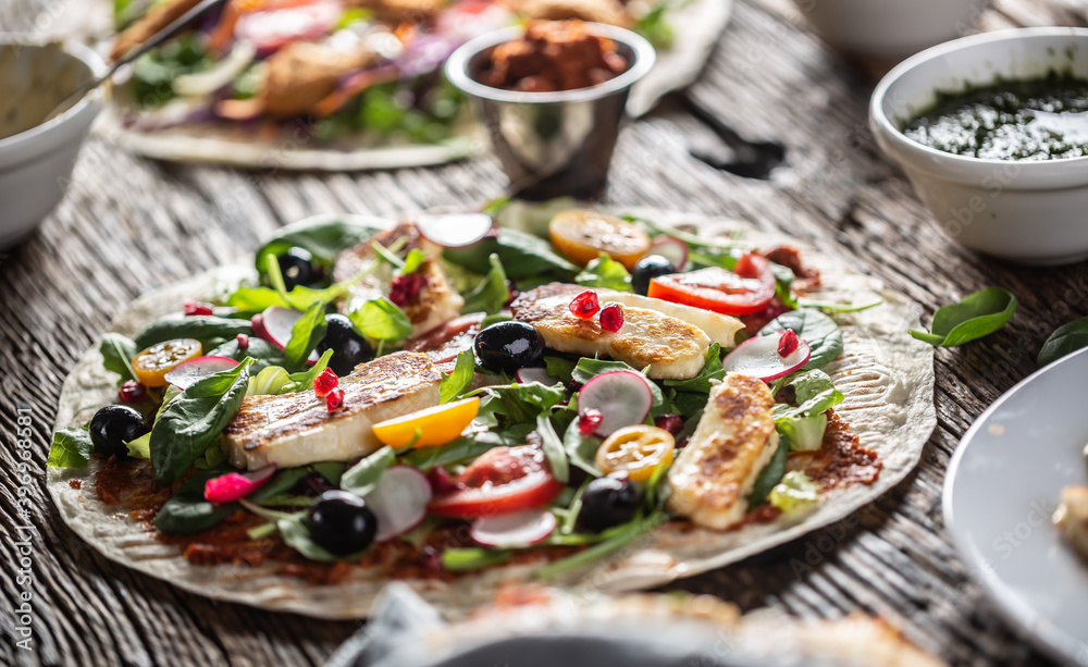 Open top vegetarian tortilla with salad, raddish, chery tomatoes, olives, pomegranate and grilled haloumi cheese Open top vegetarian tortilla with salad, raddish, chery tomatoes, olives, pomegranate and grilled haloumi cheese