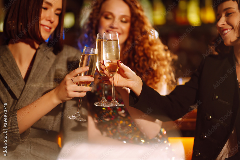 Three young Woman with champagne glasses at night club.  Women friends drinking champagne  in the bar. Party, celebration, friends, bachelorette party, birthday, winter holidays concept.