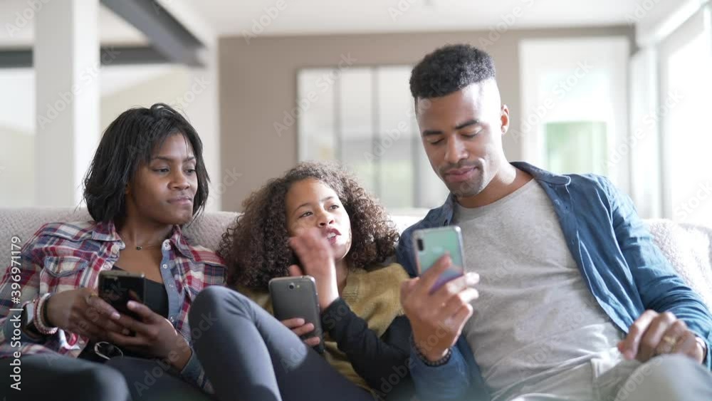 African-american family of three having fun playing with smartphones African-american family of three having fun playing with smartphones