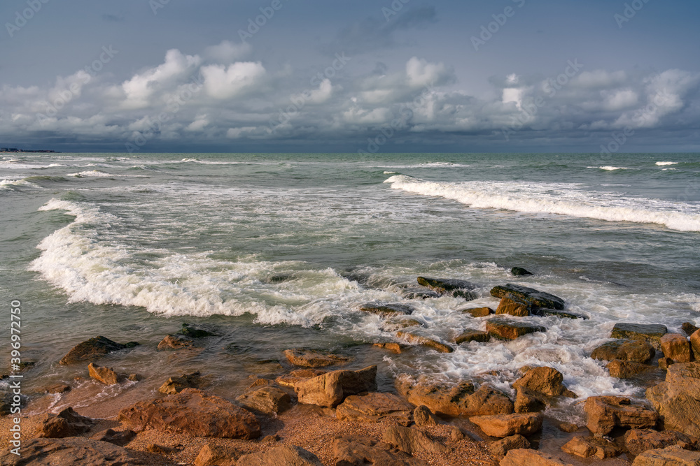 Empty rocky beach and stormy sea in cloudy weather