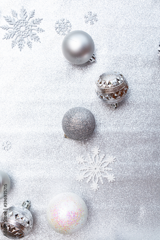 Winter background image of silvery Christmas balls and snowflakes on a silvery background.