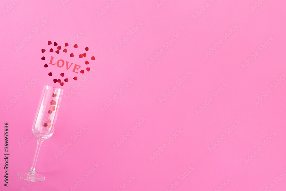Glass of champagne with red hearts and word love on a pink background. Valentines background, love, date concept with copy space, flatlay Glass of champagne with red hearts and word love on a pink background. Valentines background, love, date concept with copy space, flatlay