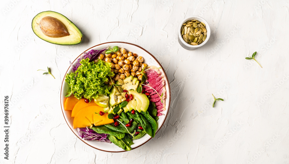 Healthy salad vegan, detox dish with roasted chickpeas, avocado, persimmon, spinach, avocado, watermelon radish and seeds. Top view, flat lay, copy space Healthy salad vegan, detox dish with roasted chickpeas, avocado, persimmon, spinach, avocado, watermelon radish and seeds. Top view, flat lay, copy space