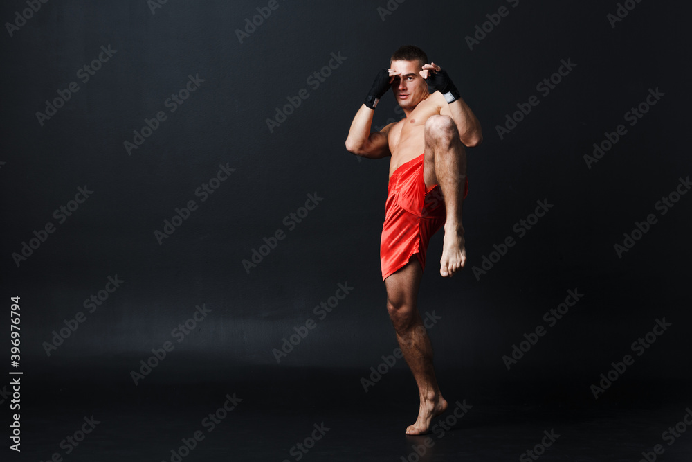 Sportsman muay thai man boxer stance ad knee kick on black background