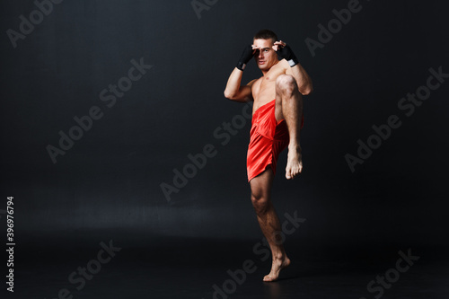 Sportsman muay thai man boxer stance ad knee kick on black background