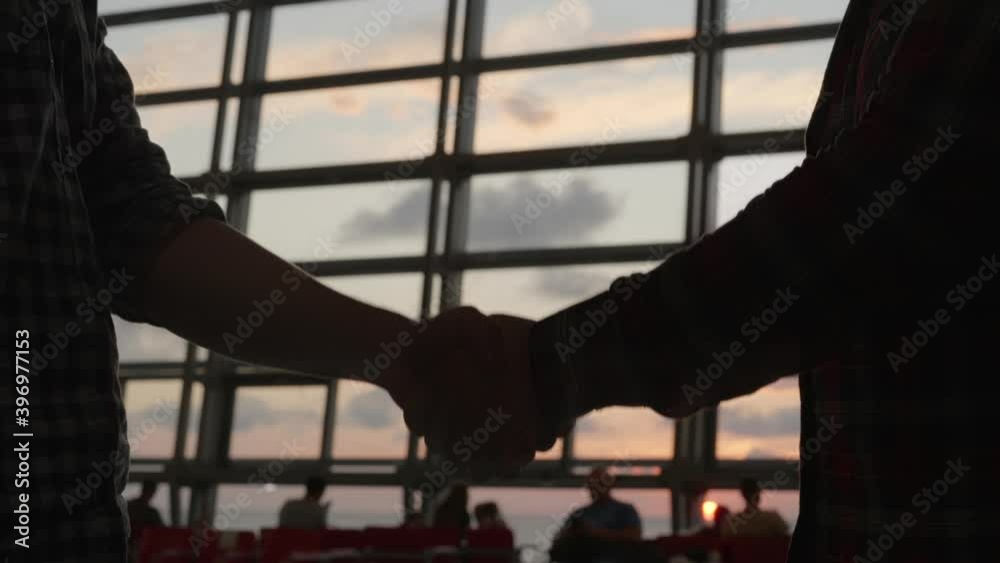 silhouette of two business peoplehandshake in modern lobby hall at sunset light. Two men meet after arrival in airport. Financial sales corporate concept background silhouette of two business peoplehandshake in modern lobby hall at sunset light. Two men meet after arrival in airport. Financial sales corporate concept background