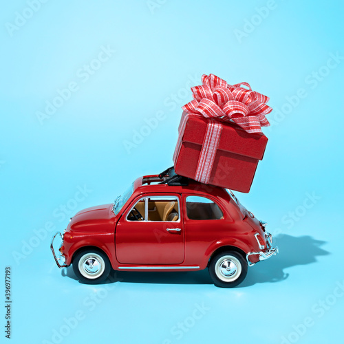 Christmas layout made with red car with wrapped gift box on the top. Minimal New Year surprise concept. © Aleksandar