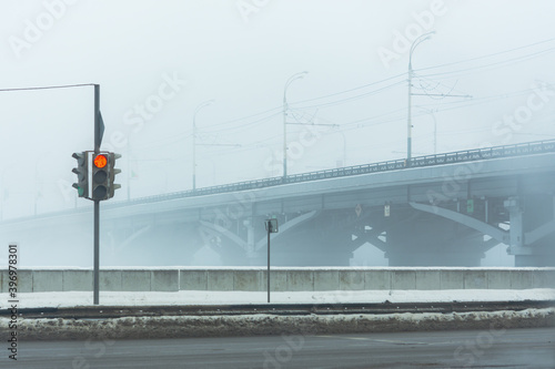 Red traffic light at the intersection in winter city. View of the intersection of the road near the Chernavsky bridge in Voronezh in winter. Empty foggy city without people. Traffic control. photo