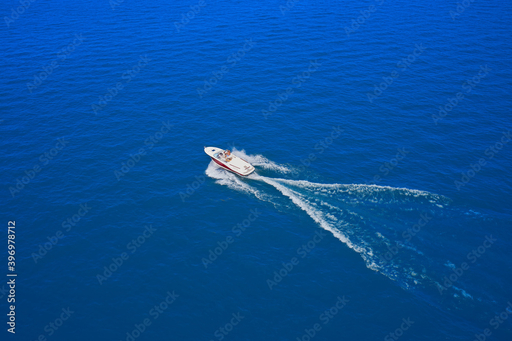 Drone view of a boat sailing at high speed. Aerial view of a boat in motion on blue water.