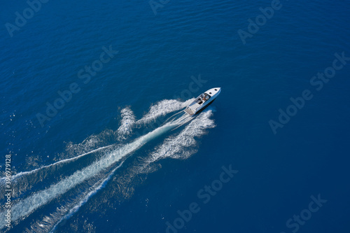 Aerial view of a boat in motion on blue water. Top view of a white boat sailing in the blue sea. luxury motor boat. Drone view of a boat sailing at high speed.