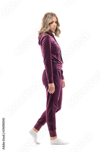 Side view of serious walking young beauty woman in leisure wear looking down at attention. Full body length isolated on white background. 
