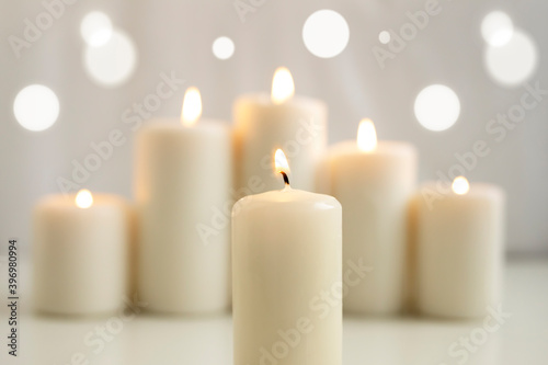Lighted candle against the background of burning candles and glare.
