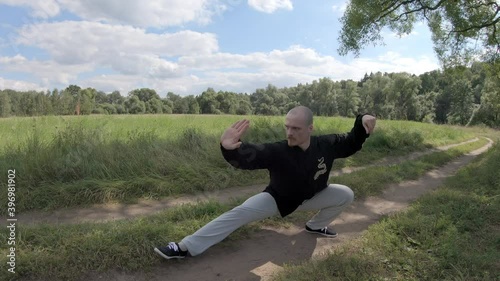 Man makes smooth movements of the Wushu style Taijiquan, and then deals a devastating blow leg photo