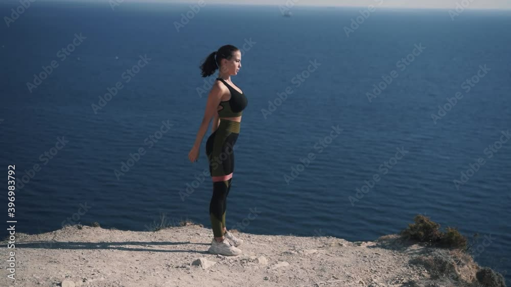 Slow motion beautiful young woman in sportswear doing squats with elastic band Slow motion beautiful young woman in sportswear doing squats with elastic band